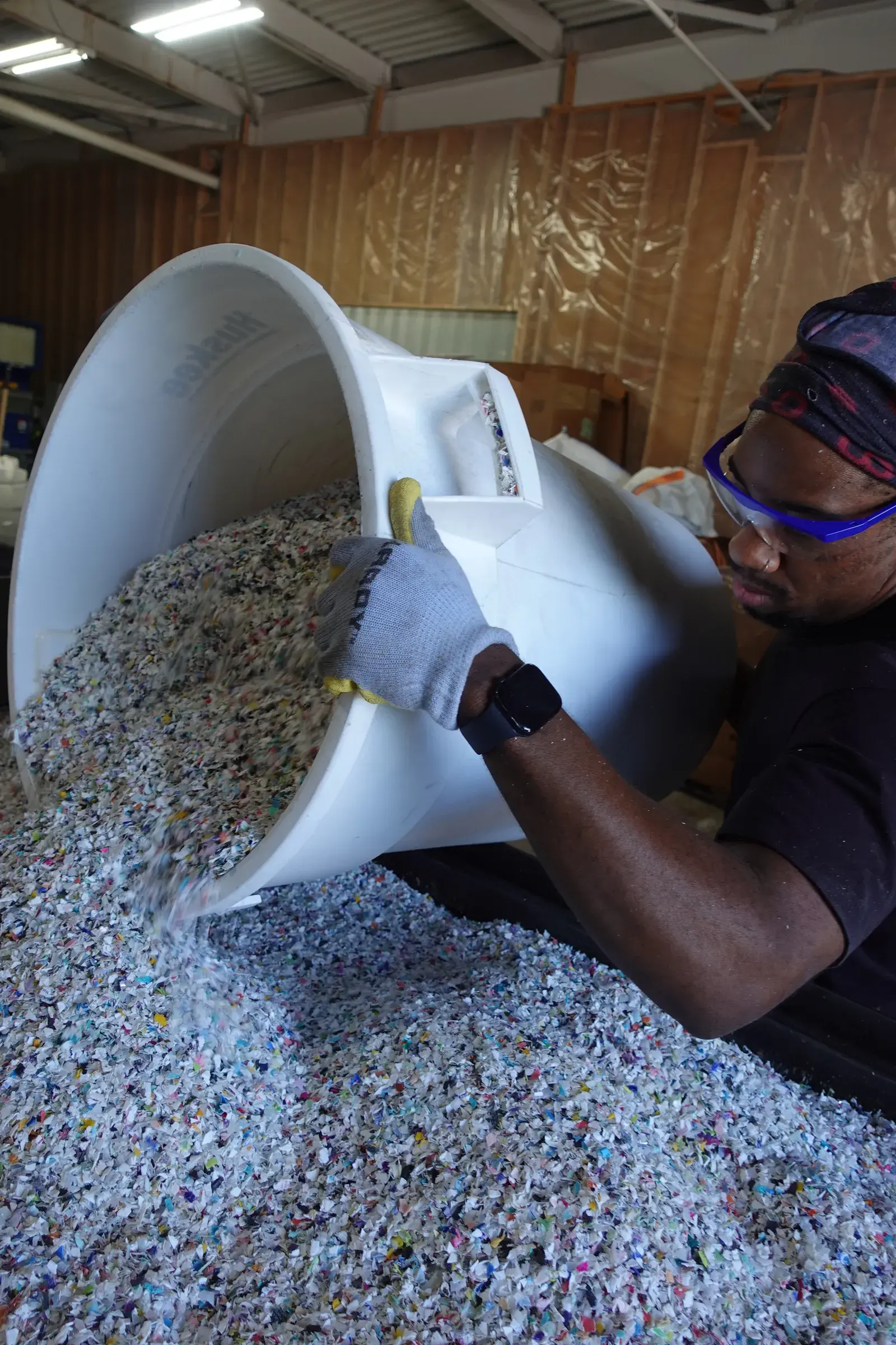 A Marble Plastics team member pours a bin of shredded post-consumer plastic onto the feedstock pile.