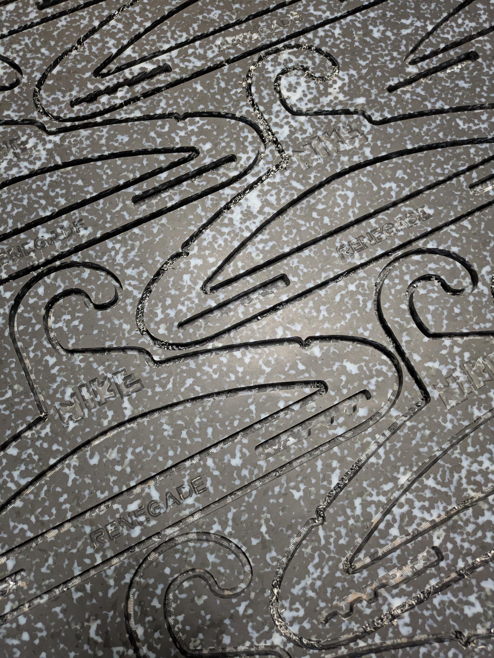 CNC-cut script and curlique forms in a Marble Plastics Graphite sheet.