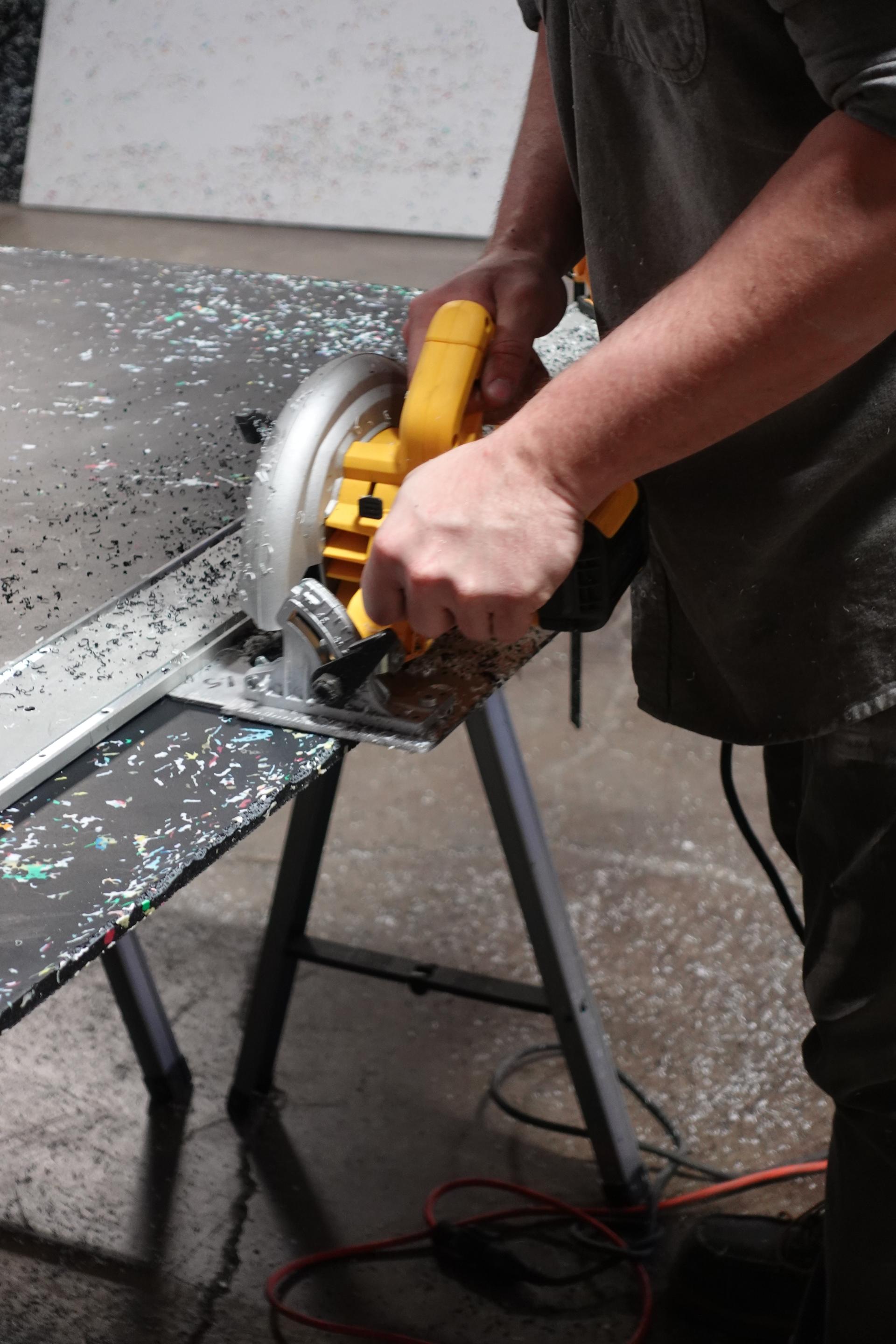 Track saw cutting a beveled edge on a confetti-fleck Marble Plastics sheet.