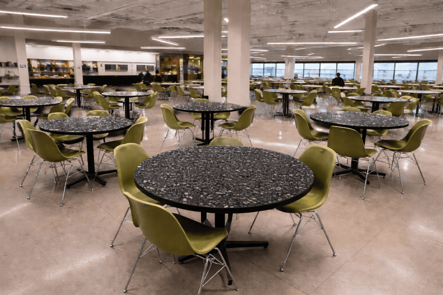 Replay Stride dining tabletops in a cafeteria, paired with green chairs.