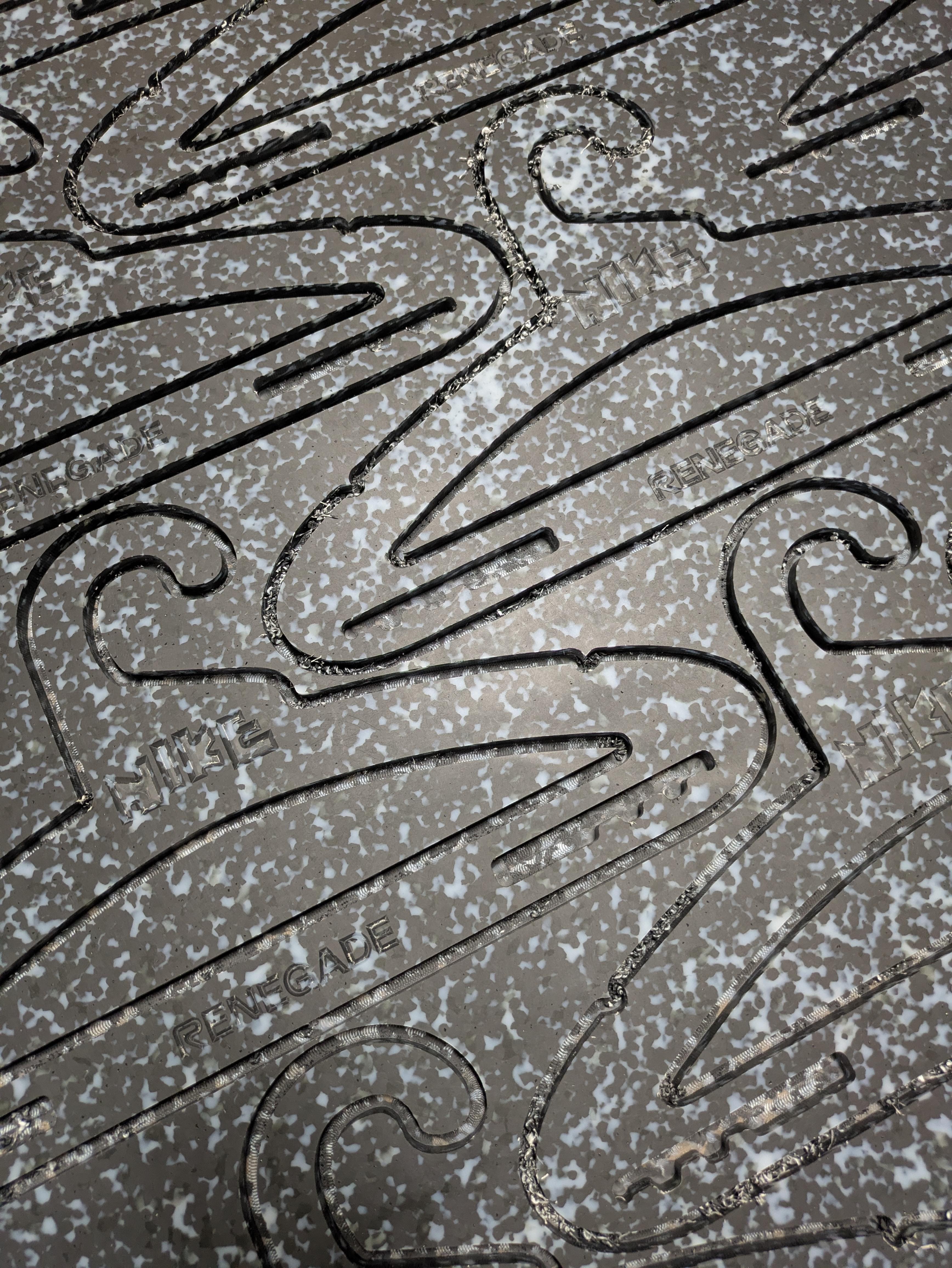 CNC-cut script and curlique forms in a Marble Plastics Graphite sheet.